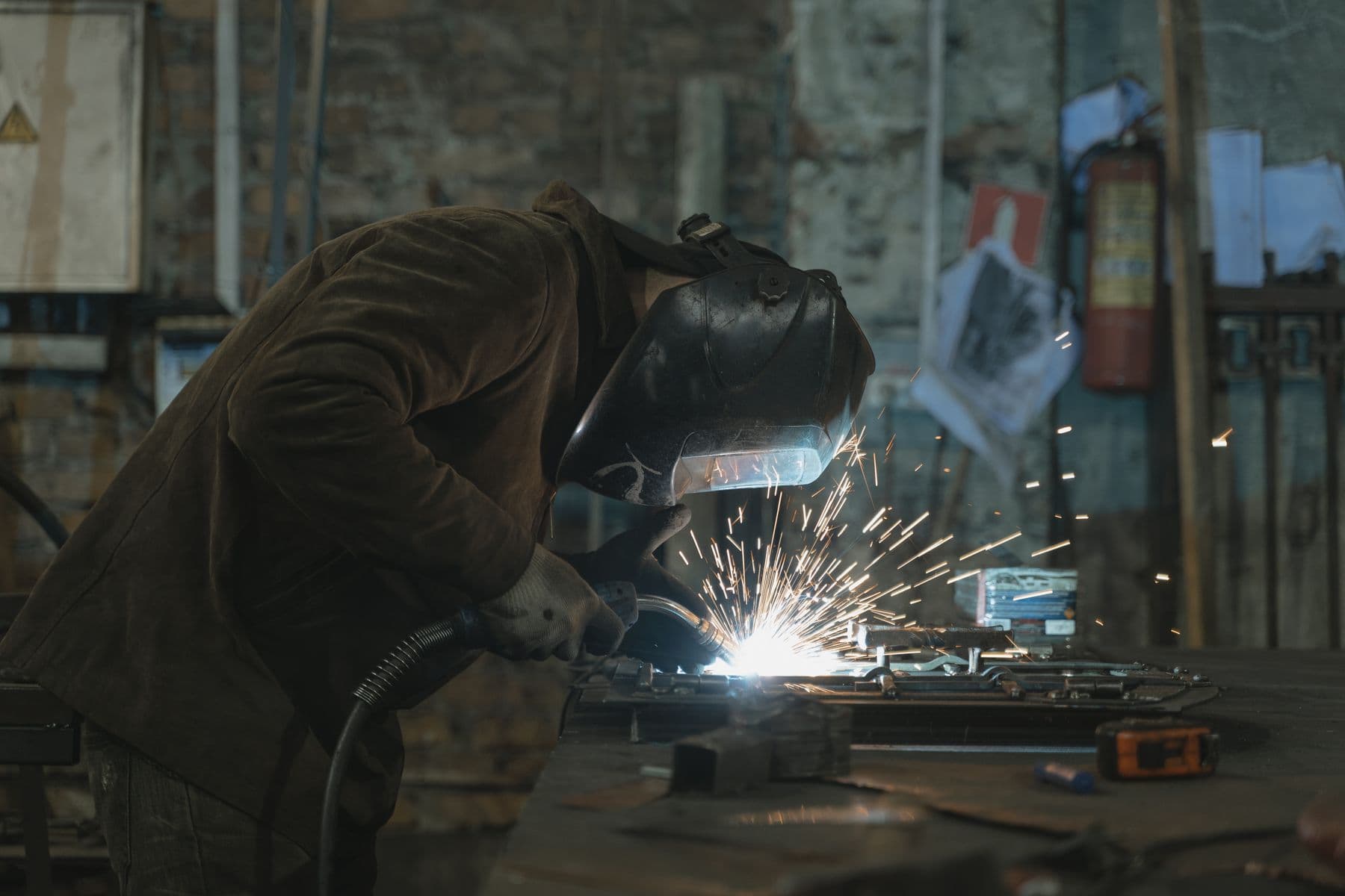 Soudeur au travail dans un atelier de serrurerie, gerbe d’étincelles sur une pièce en cours d’assemblage.